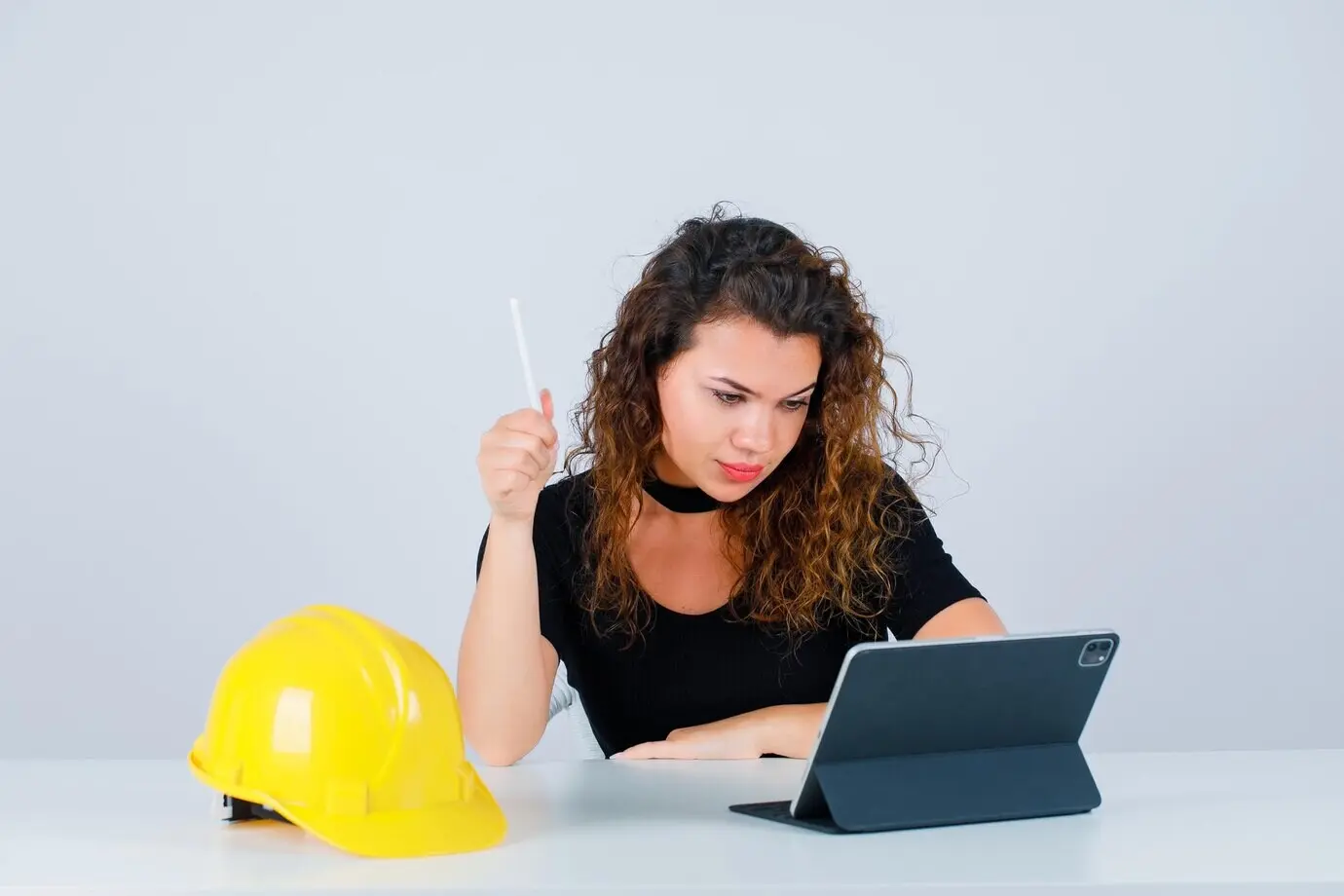 Eine junge Ingenieurin spricht in einem Videoanruf und hält dabei einen Stift vor weißem Hintergrund.