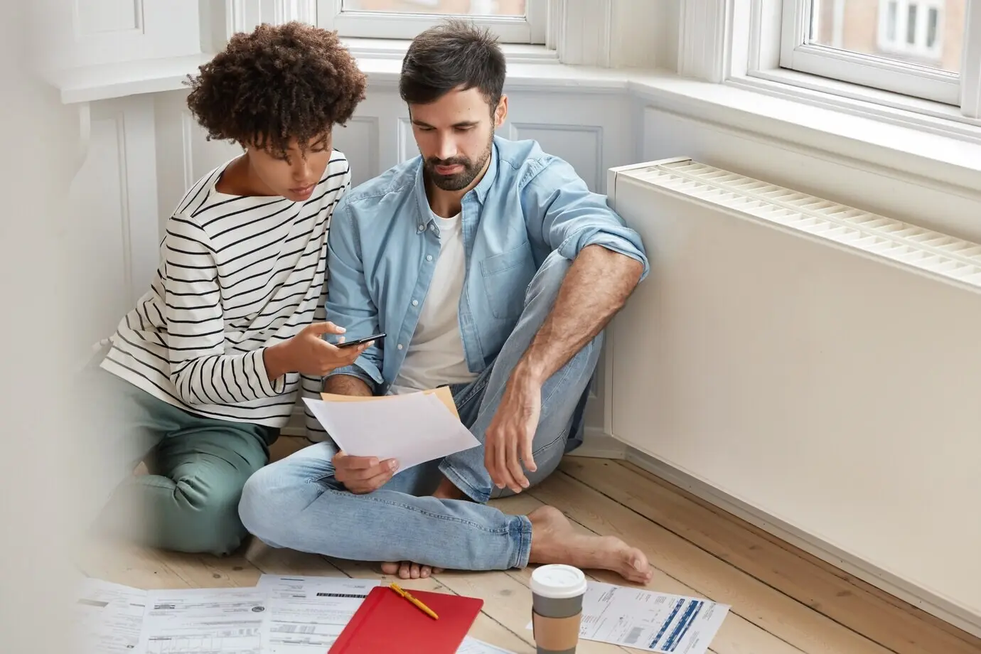 Eine unbeschwerte Frau und ein unbeschwerter Mann unterschiedlicher ethnischer Herkunft prüfen Unterlagen.